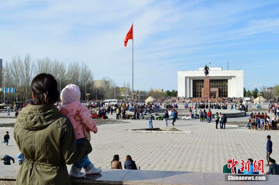 3月21日是傳統節日諾魯孜節，在吉爾吉斯斯坦，這是吉爾吉斯族、哈薩克族、烏孜別克族、維吾爾族等民族的共同節日。“諾魯孜”意為“新的一天”或“新的光明”。當日，在吉爾吉斯斯坦比什凱克市，各民族民眾前往市中心的阿拉套廣場慶祝諾魯孜節。圖為一位當地民眾帶著孩子游玩。