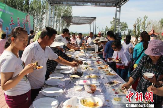 在新疆瑪納斯縣蘭州灣鎮首屆金土豆文化采摘節上，民眾品嘗“土豆全席宴”。　戚亞平 攝
